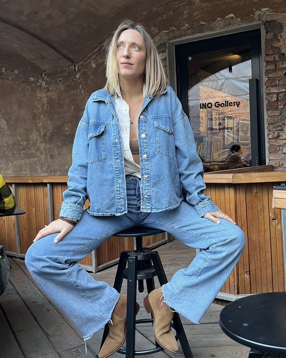 Barbara Shakina seated on a stool in a denim jacket and wide-leg jeans