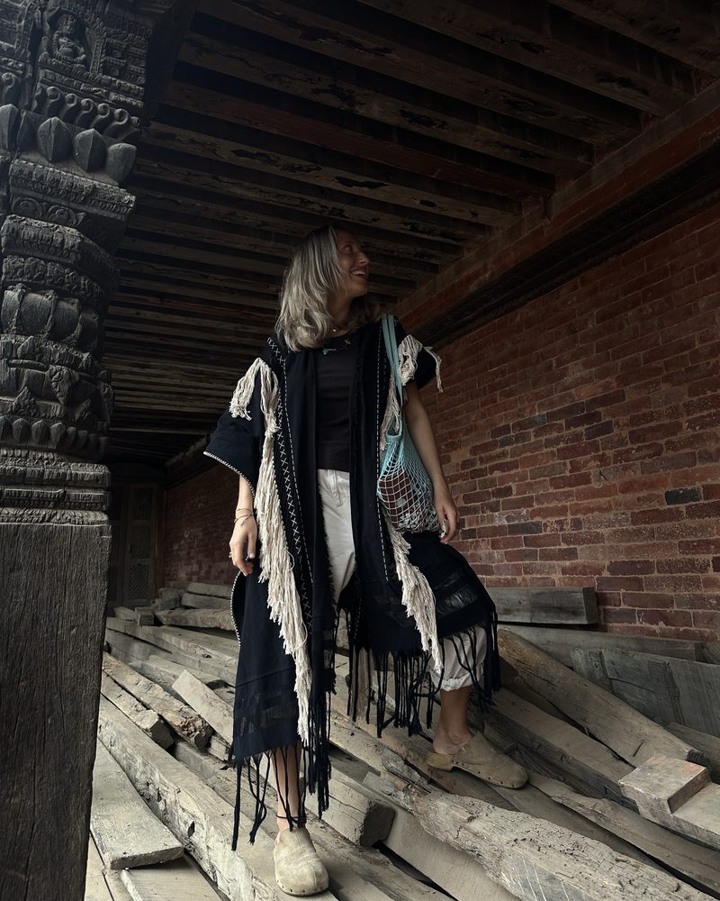 Black fringed kimono over white in a carved wooden temple